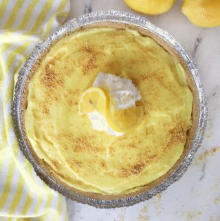 a lemon pudding pie next to a yellow hand towel on a quartz countertop