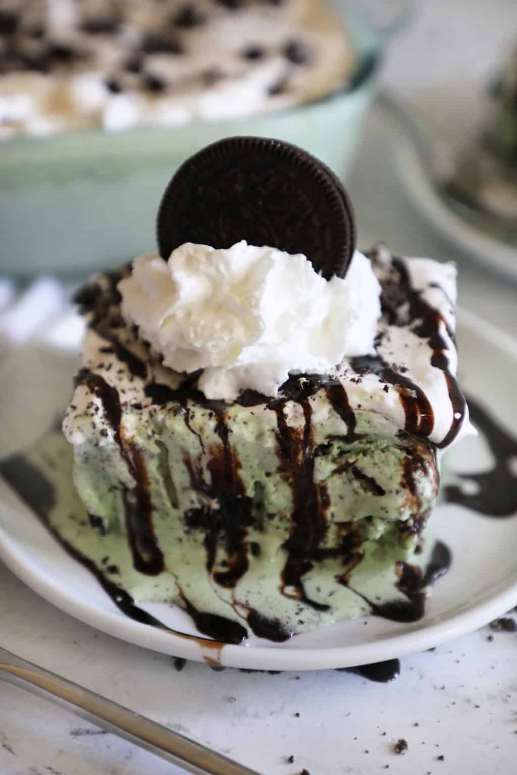 ice cream cake garnished with chocolate syrup, whipped cream and an oreo