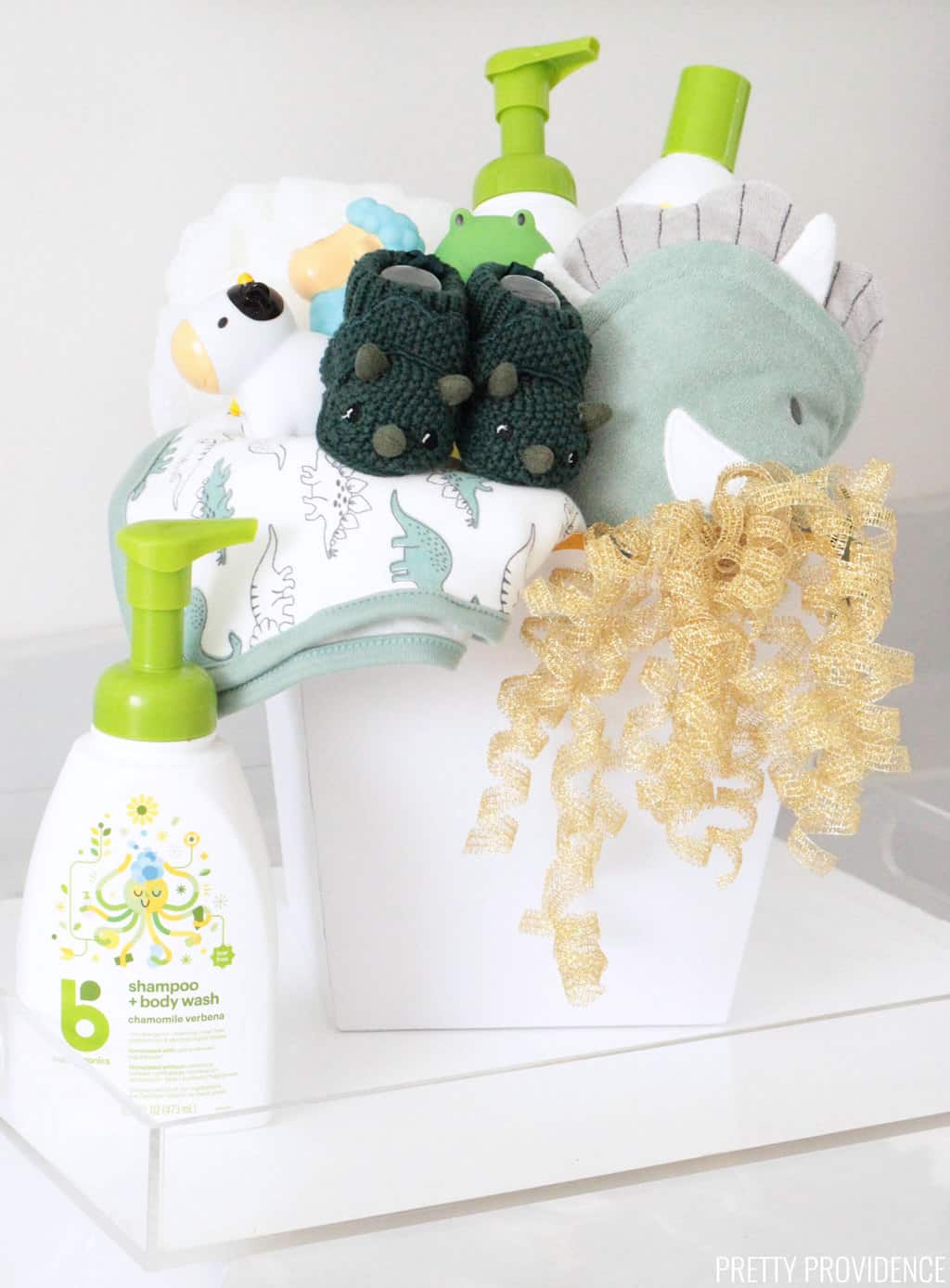 Baby Shower Gift basket with dinosaur towels, green dinosaur slippers, bath toys, baby shampoo and lotion