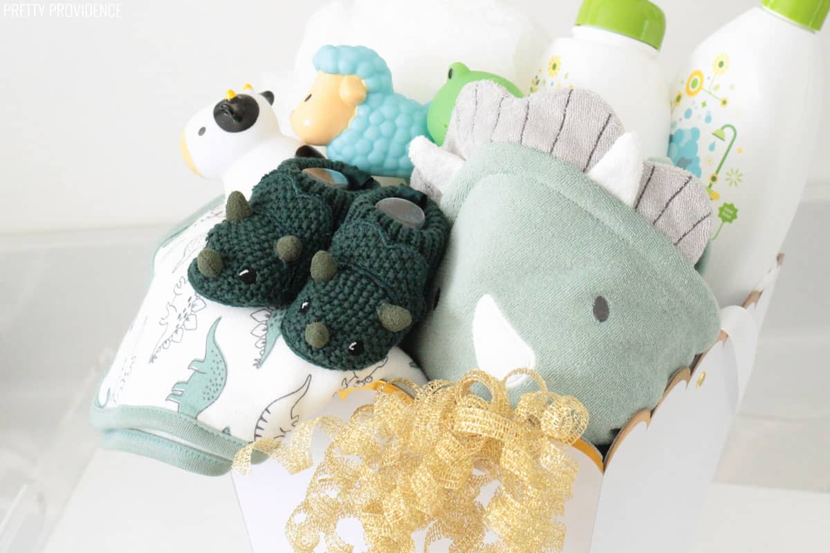 Baby shower gift basket with dinosaur bath towels, knit booties, toys and baby shampoo