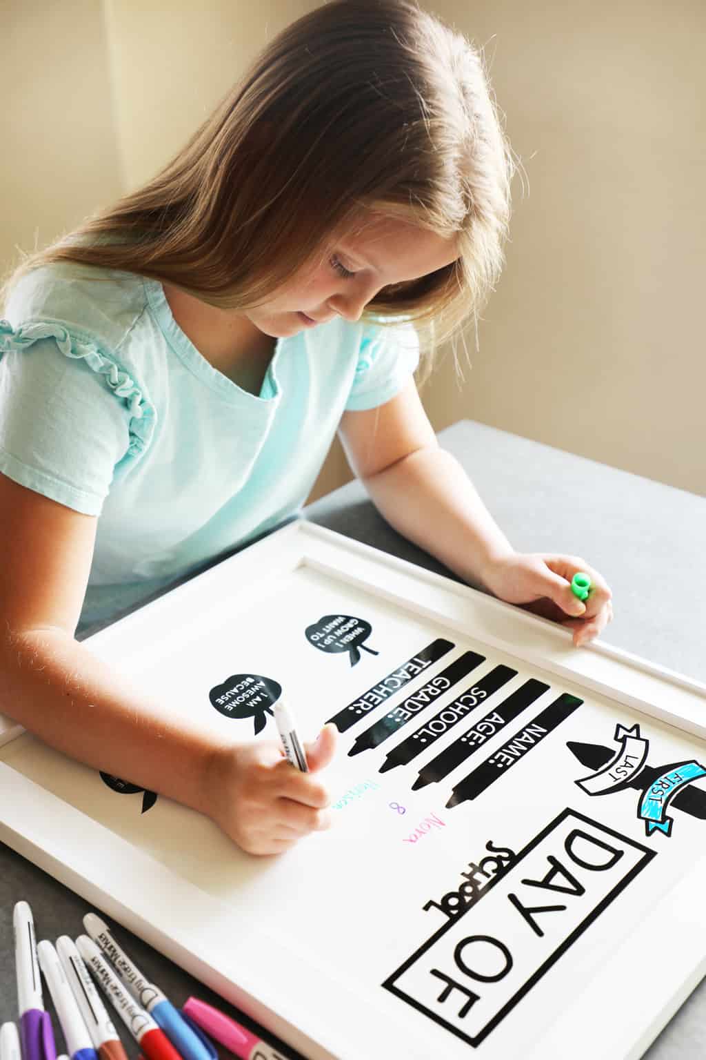 girl writing on a first day of school whiteboard