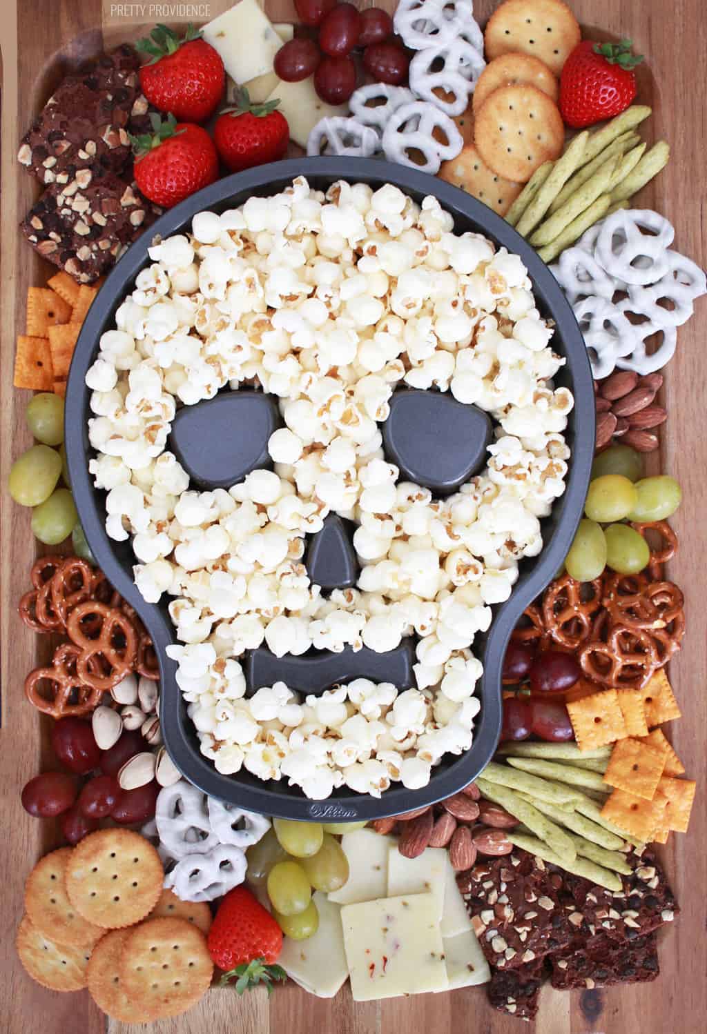 Halloween charcuterie board with a skull cake pan full of popcorn