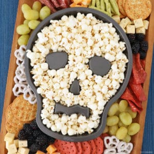 Halloween charcuterie board with a skull cake pan full of popcorn