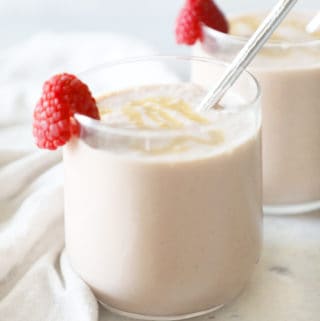 two peanut butter and jelly smoothies with raspberries for garnish