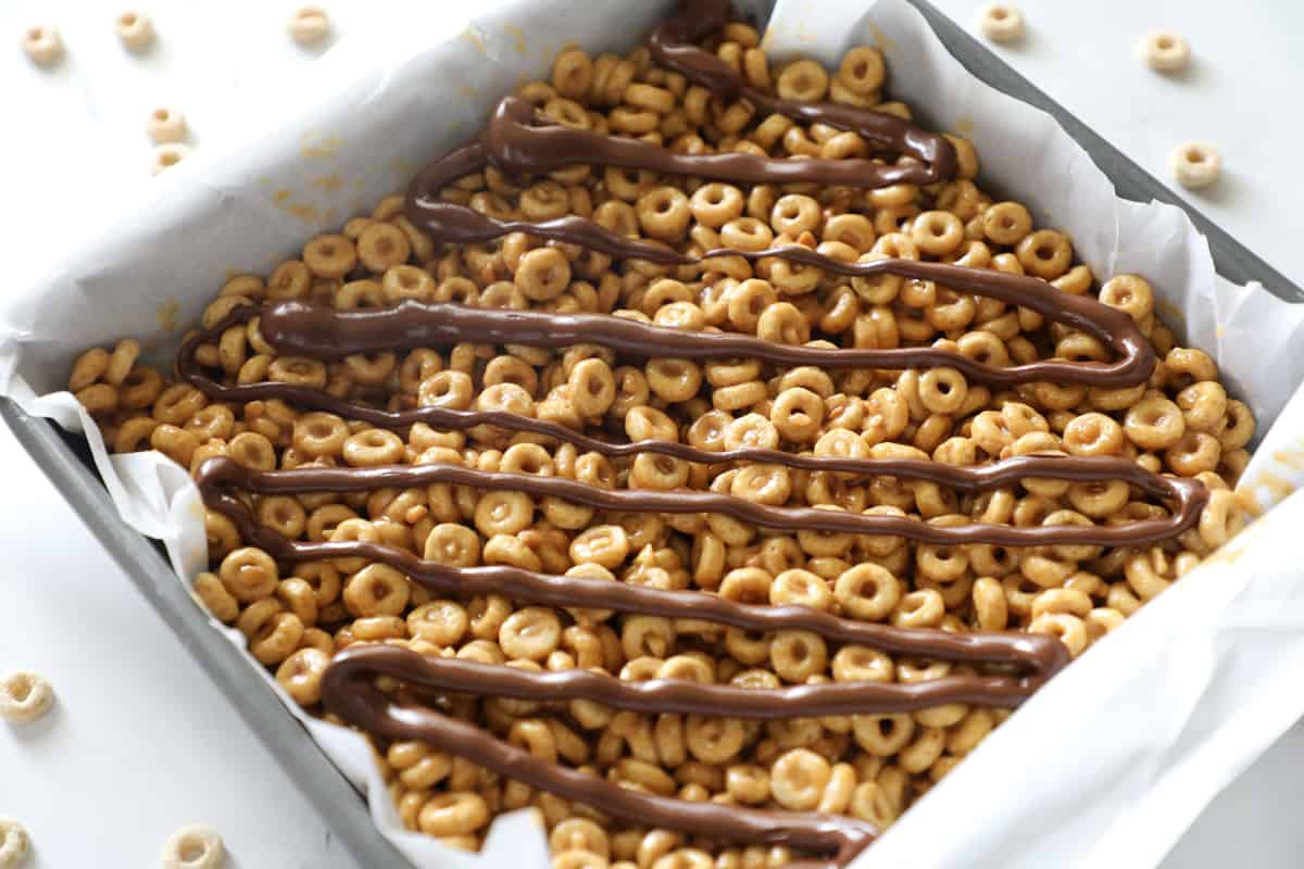 fresh melty chocolate just drizzled on pan of cheerio bars
