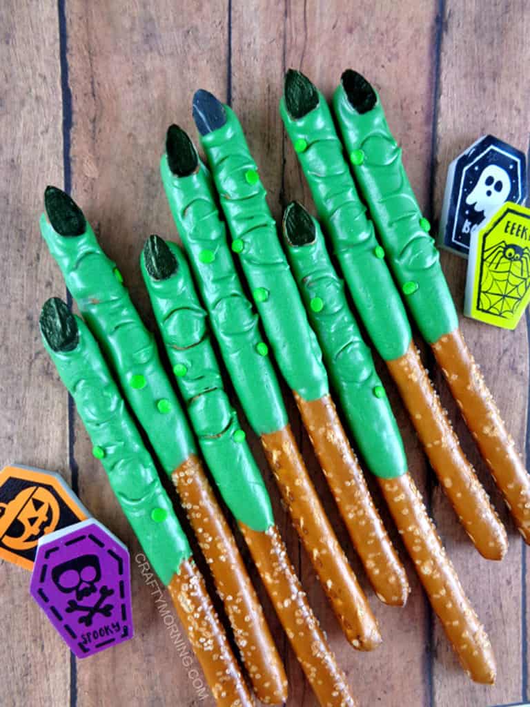 Pretzel sticks with green candy coating and black fingernails made to look like witches fingers