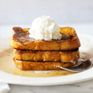 three slices of pumpkin French toast stacked on a white plate