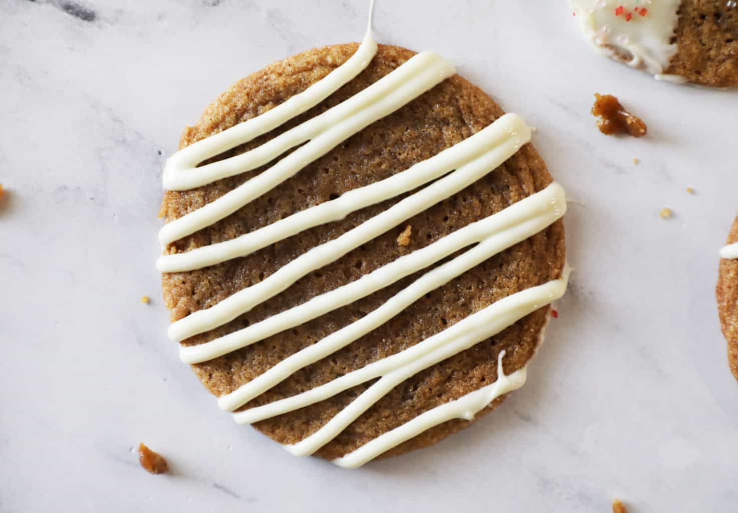 a ginger snap with white chocolate drizzle on a marble countertop