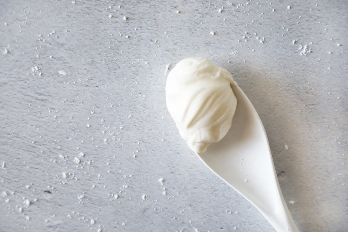 homemade cream cheese frosting on a white spoon