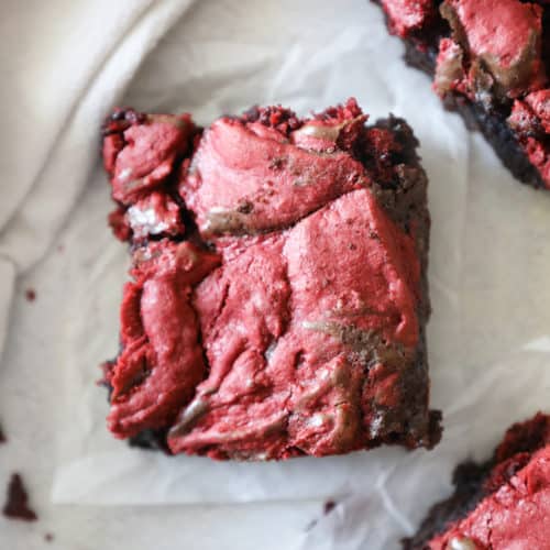 a bird's eye view of a red velvet brownie on a square of parchment paper