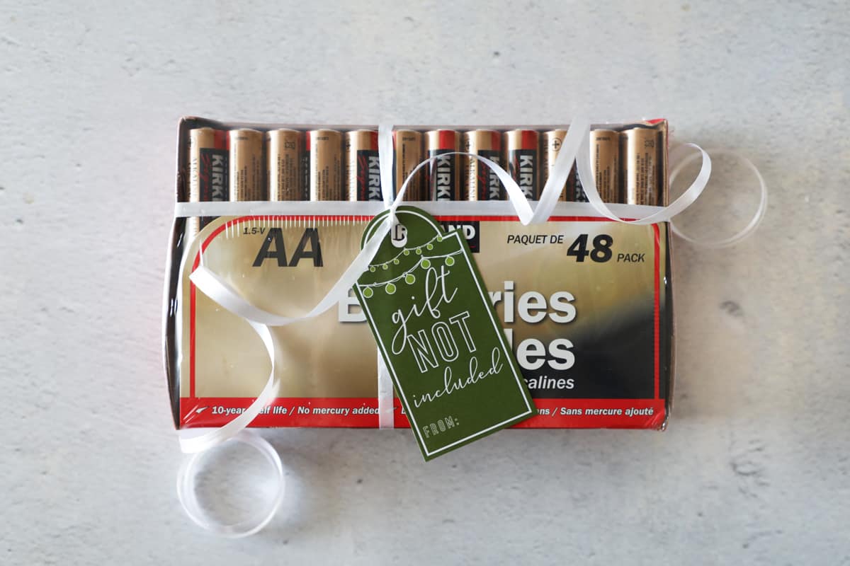 batteries with ribbon and a gift tag laying on the counter
