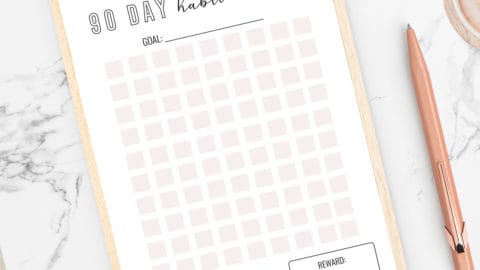 a habit tracker with pink squares next to a rose gold pen