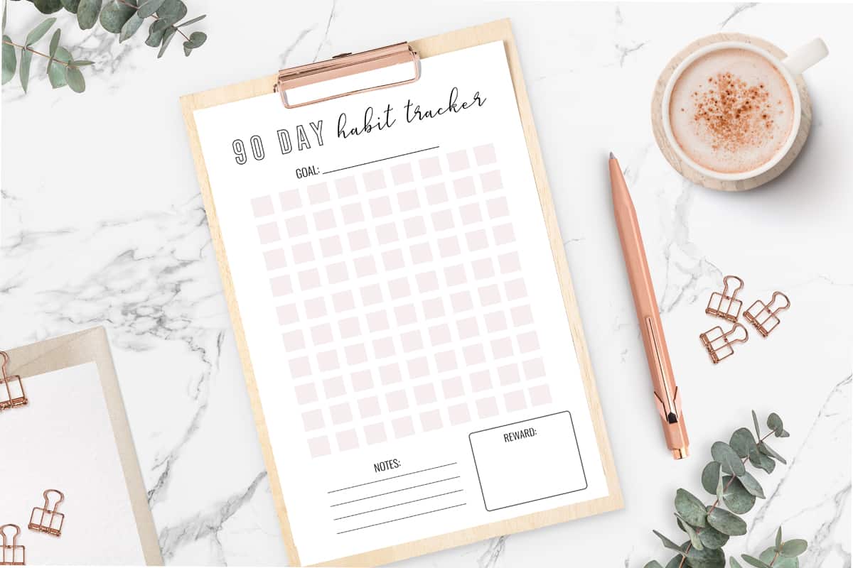 a pretty habit tracker printable next to coffee and a pen