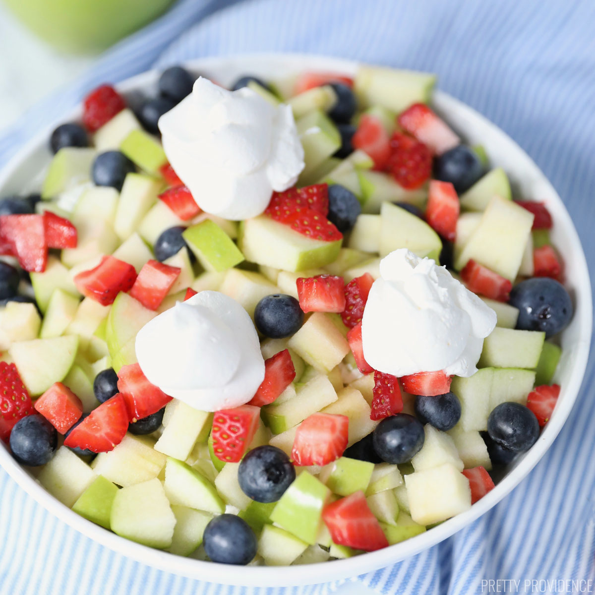 Fruit Salad made of granny smith apples, blueberries, strawberries with dollops of cool whip on top