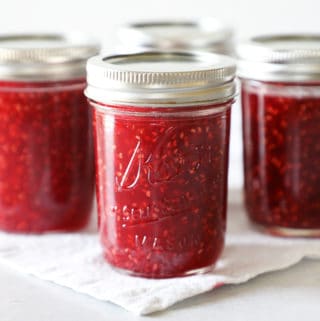 four small mason jars full of homemade raspberry jam in a diamond formation