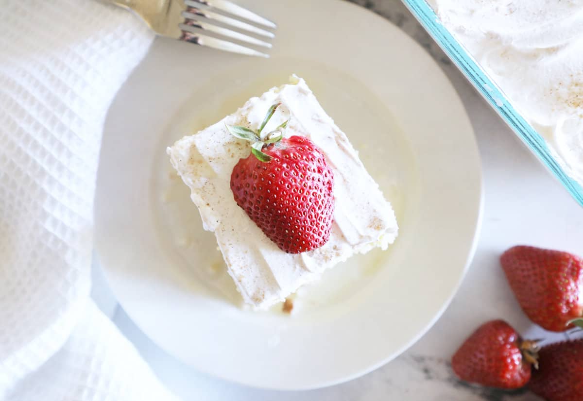 Birds eye view of an easy tres leches cake with a fork next to it on a small white plate. 