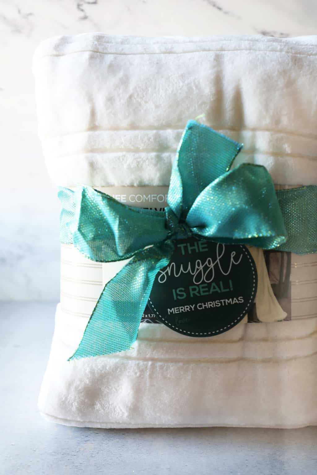 a white blanket wrapped in a big emerald green ribbon