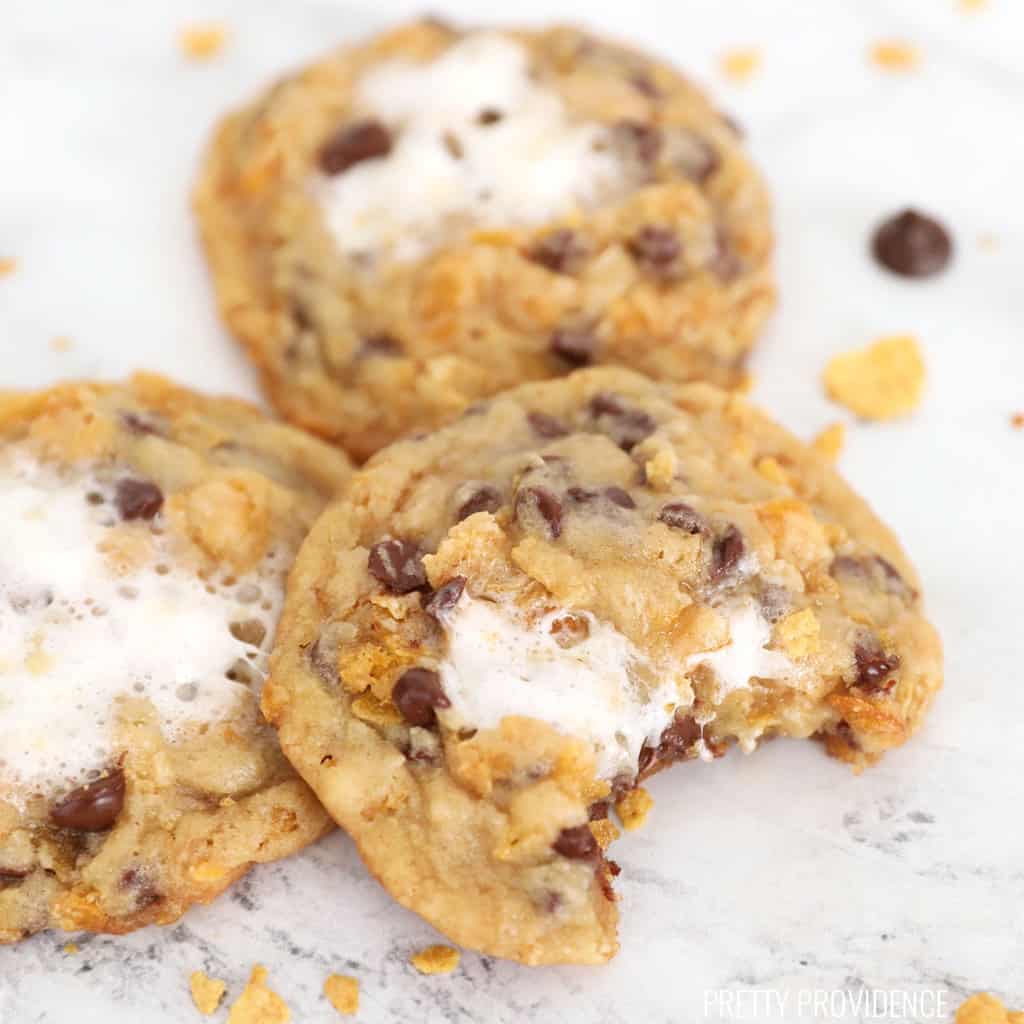 a cornflake chocolate chip marshmallow cookie with a bite taken out of it resting against two other cookies.