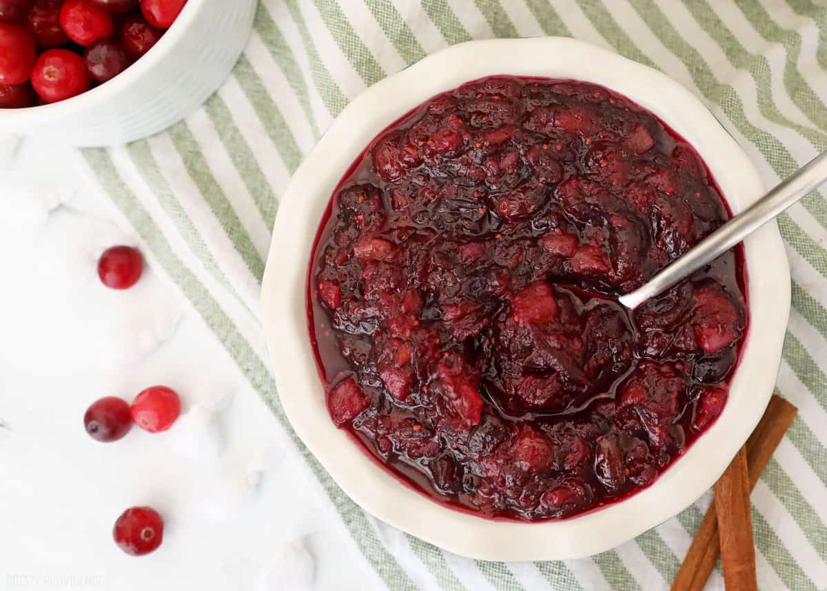 cranberry sauce in a white dish with fresh cranberries next to it.