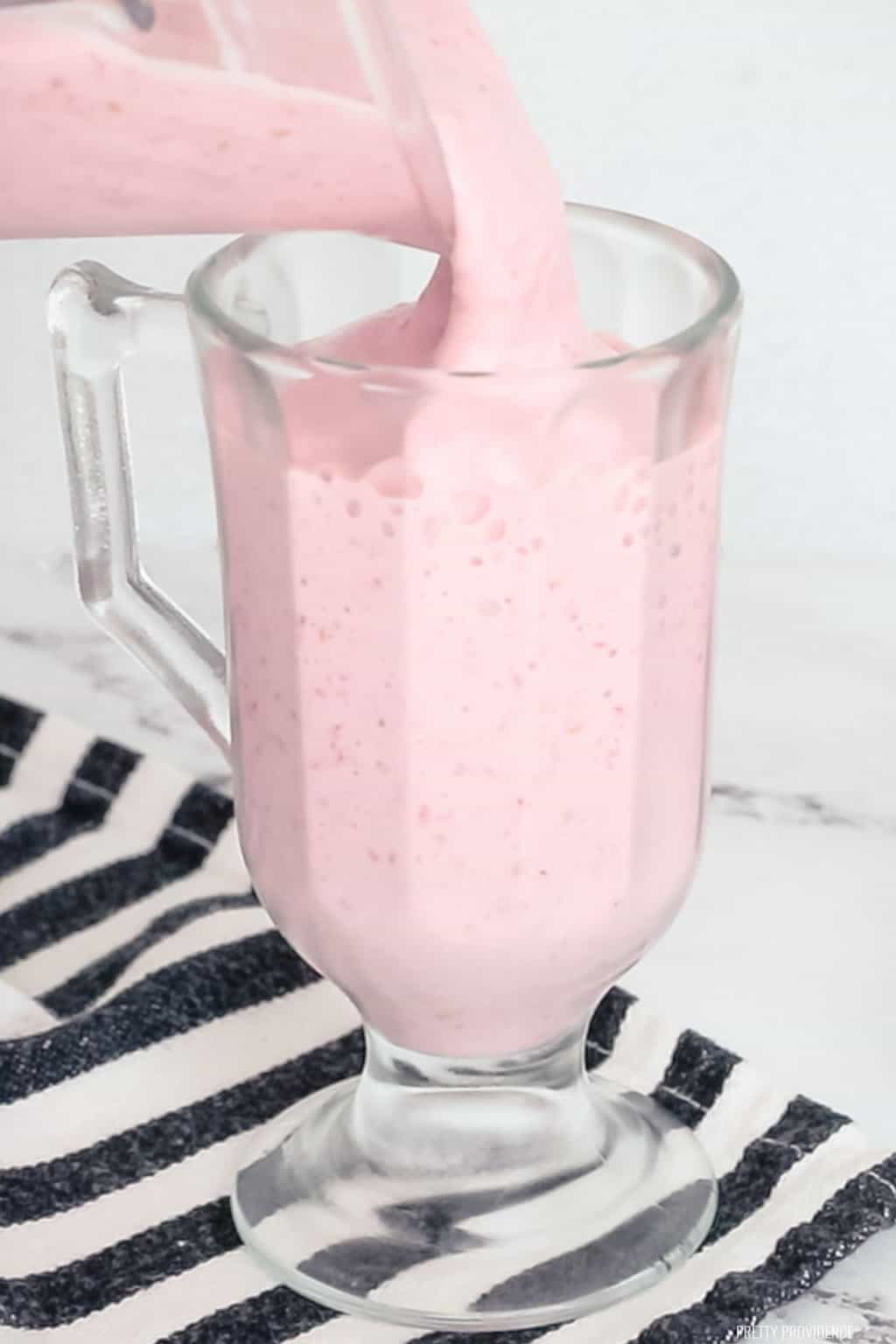 raspberry milkshake being poured into a glass.
