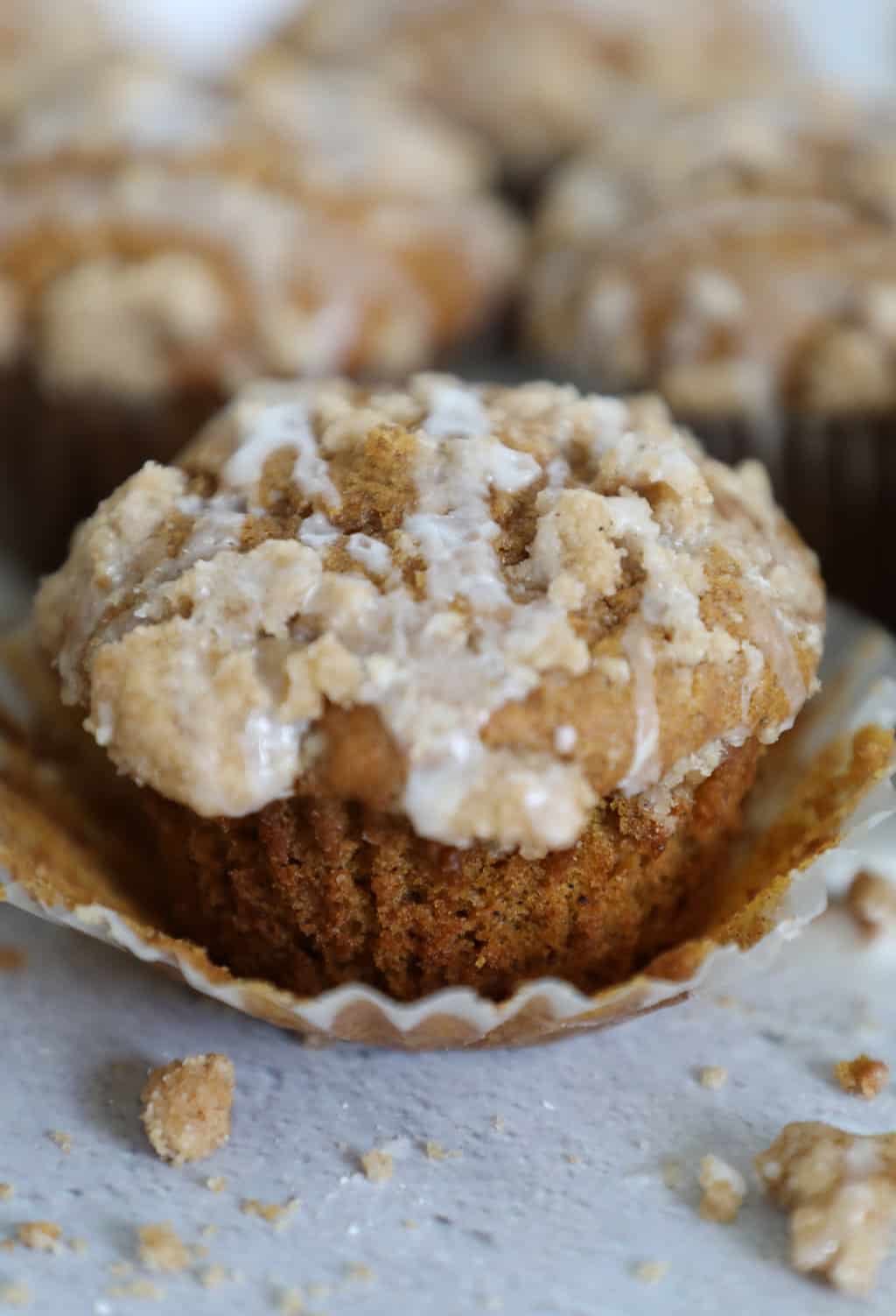 A close up vertical image of a pumpkin muffin with crumb topping. 
