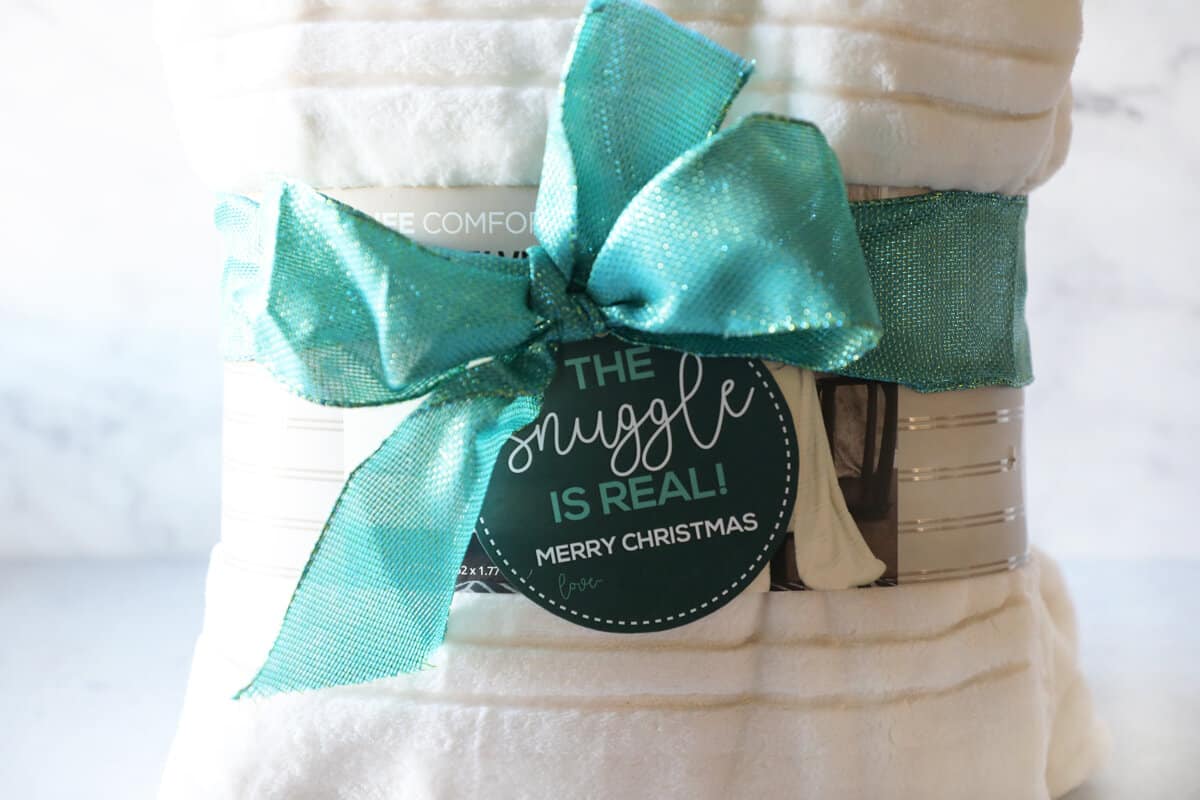 a cream colored blanket with a ribbon and printable tag. 