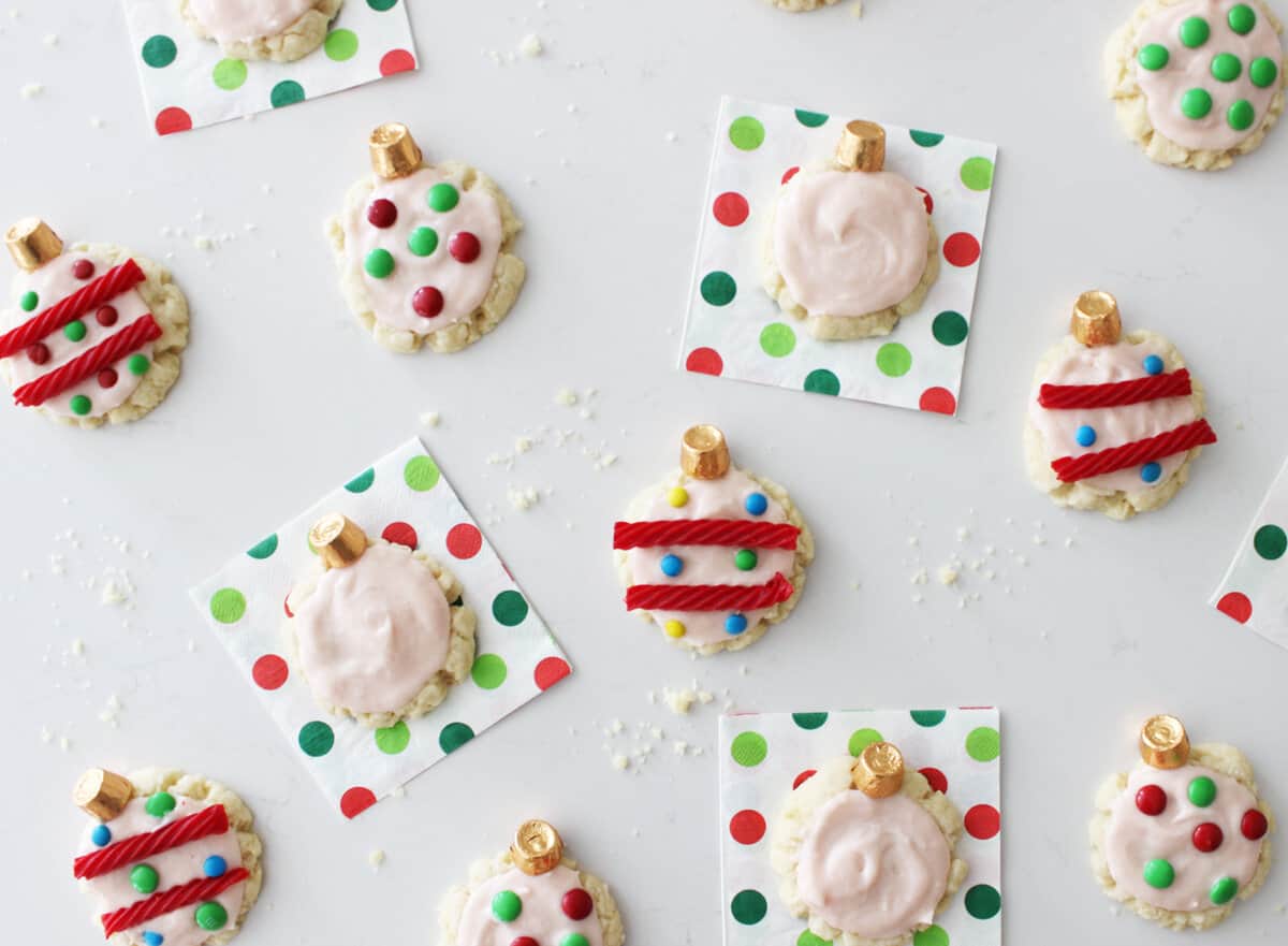 Several sugar cookies decorated like ornaments on Christmas napkins.