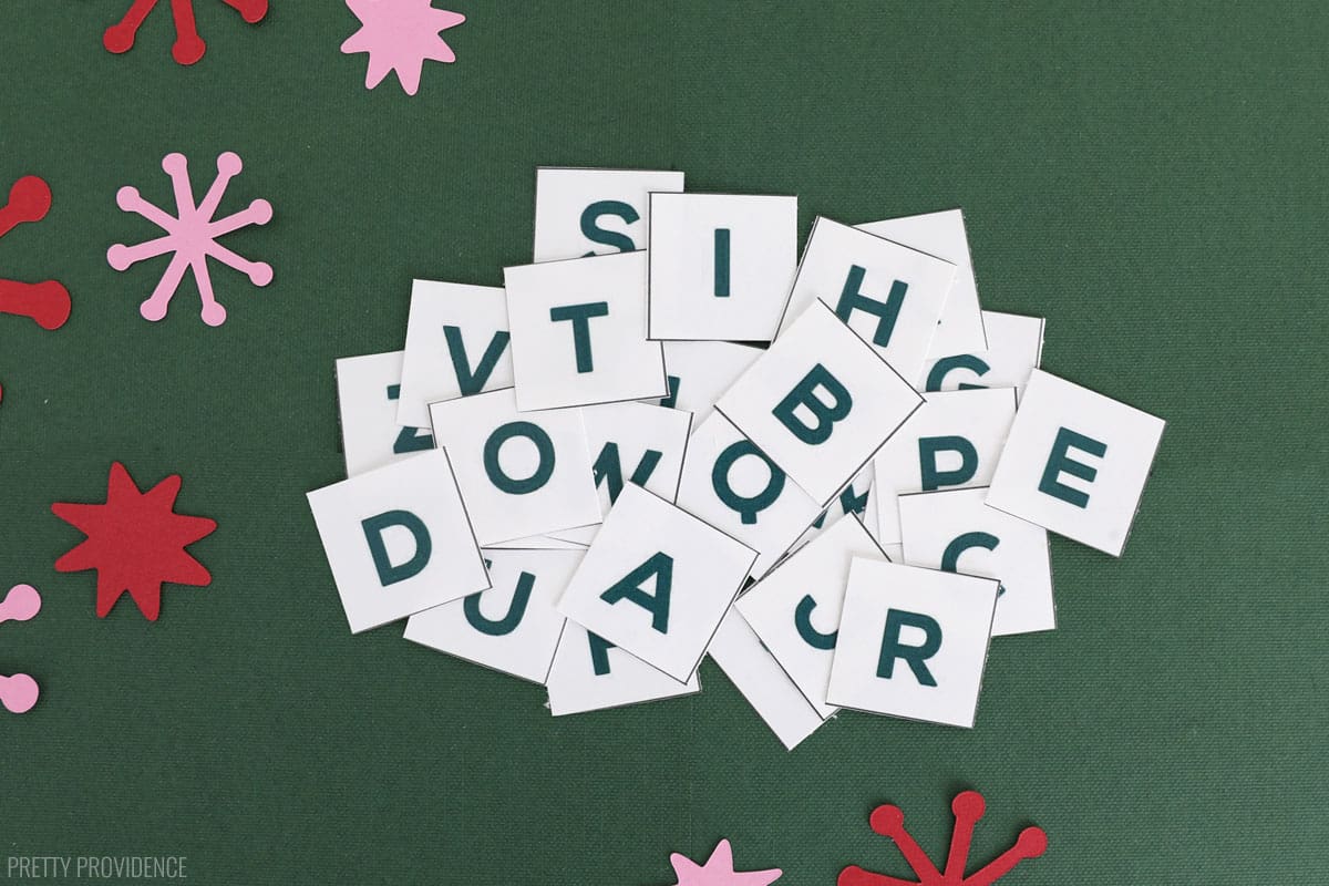 alphabet letters printed and cut out of paper on a green surface.