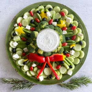 A veggie tray shaped like a wreath for christmas with ranch dip in the center.