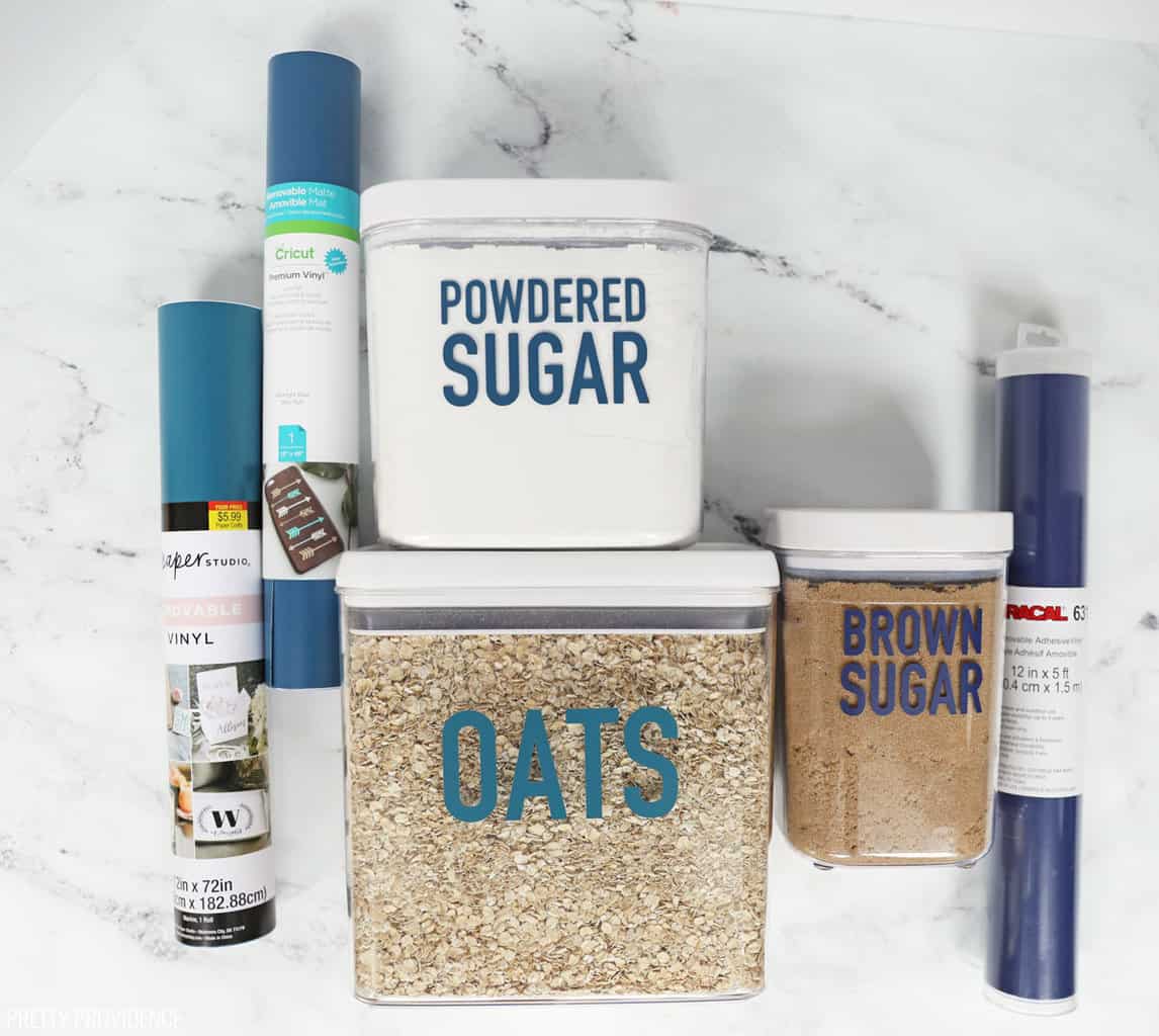 Oats, powdered sugar and brown sugar in clear containers with blue vinyl labels on them and the rolls of vinyl used next to them.. 