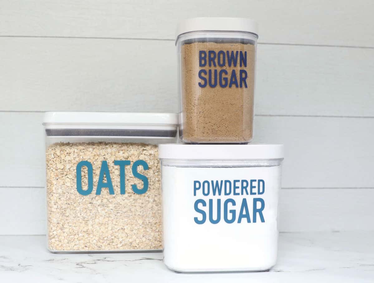 Oats, powdered sugar and brown sugar in clear containers with blue vinyl labels on them. 