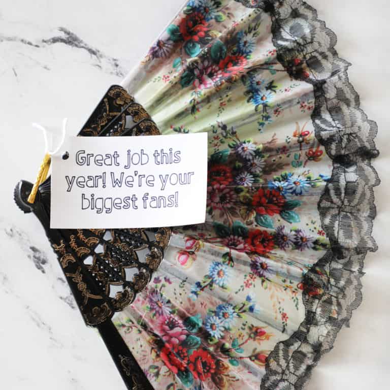 Close up image of a pretty fan open wide with a gift tag on it.