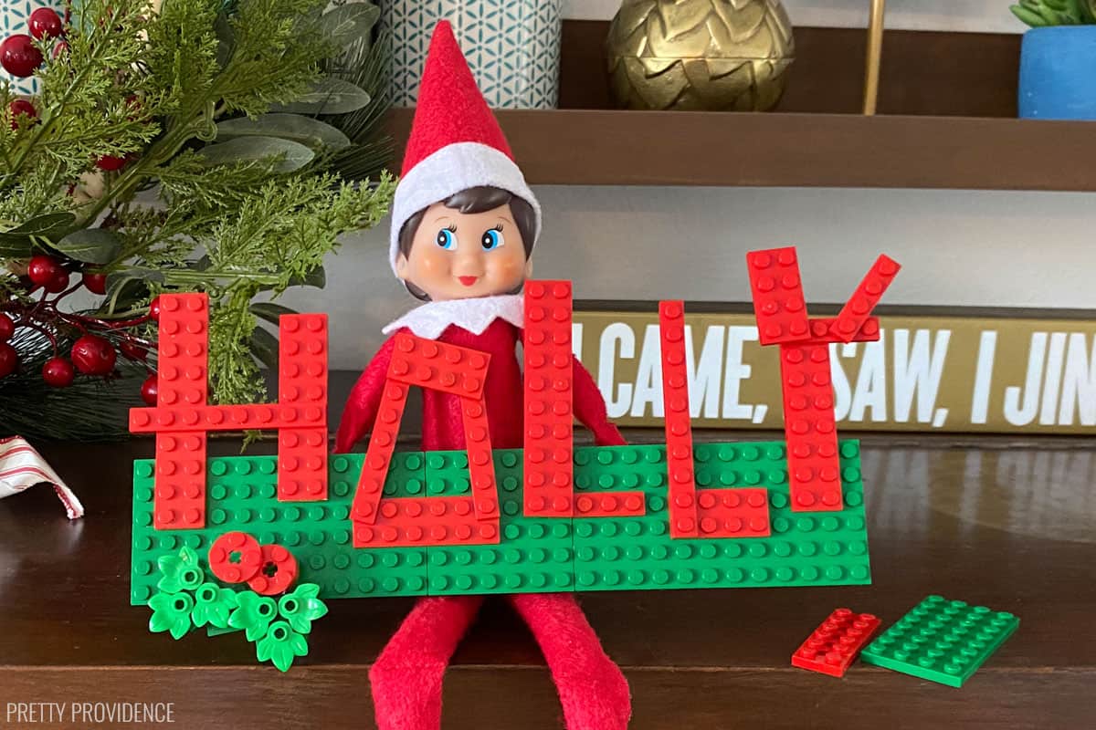 Elf on the Shelf with the name 'Holly' spelled out with lego.