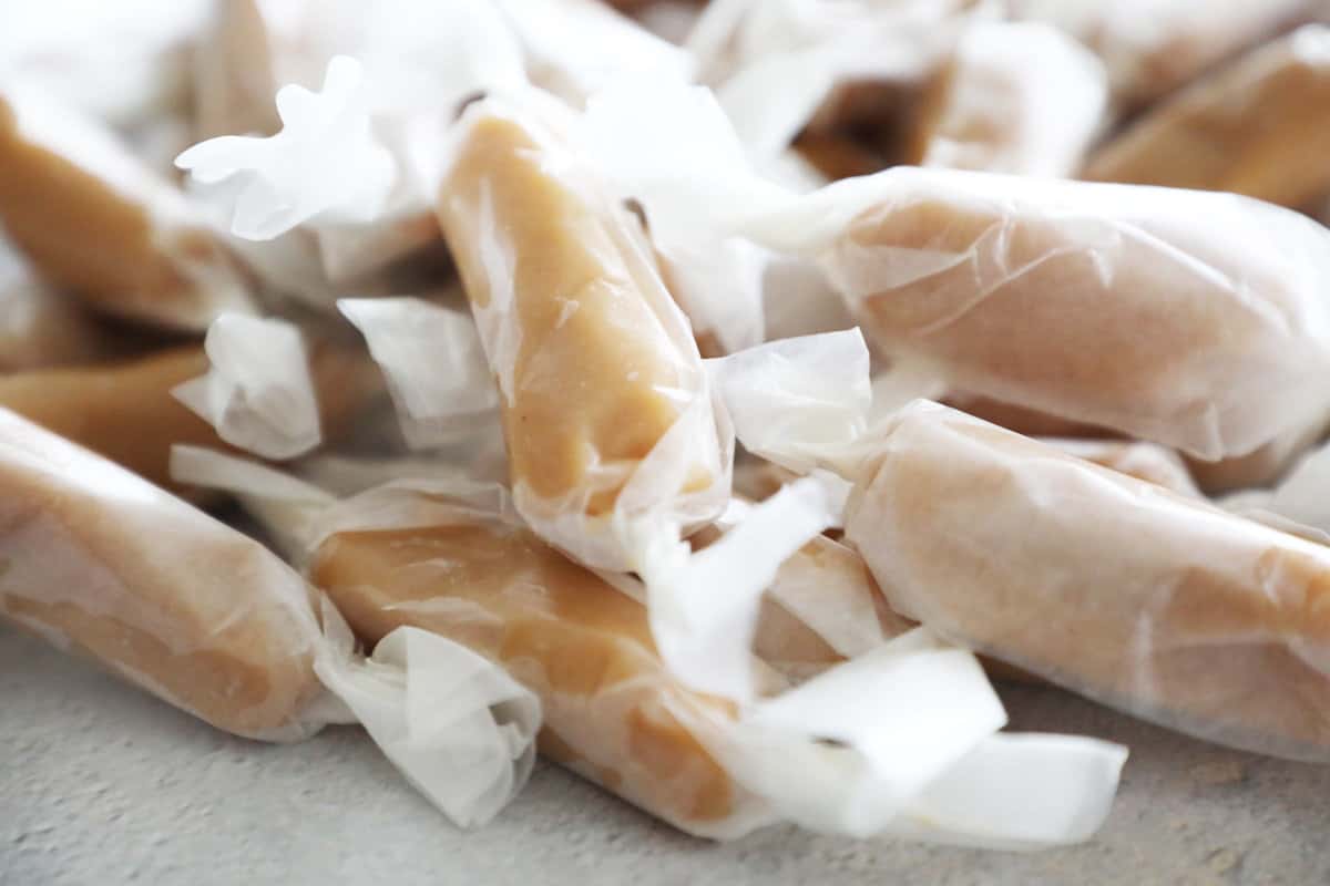 Side view of homemade caramels wrapped in parchment paper. 