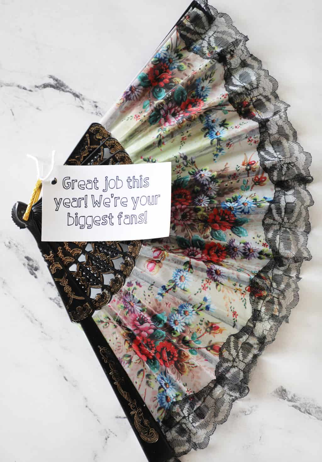 A floral fan spread wide with a white gift tag attached.
