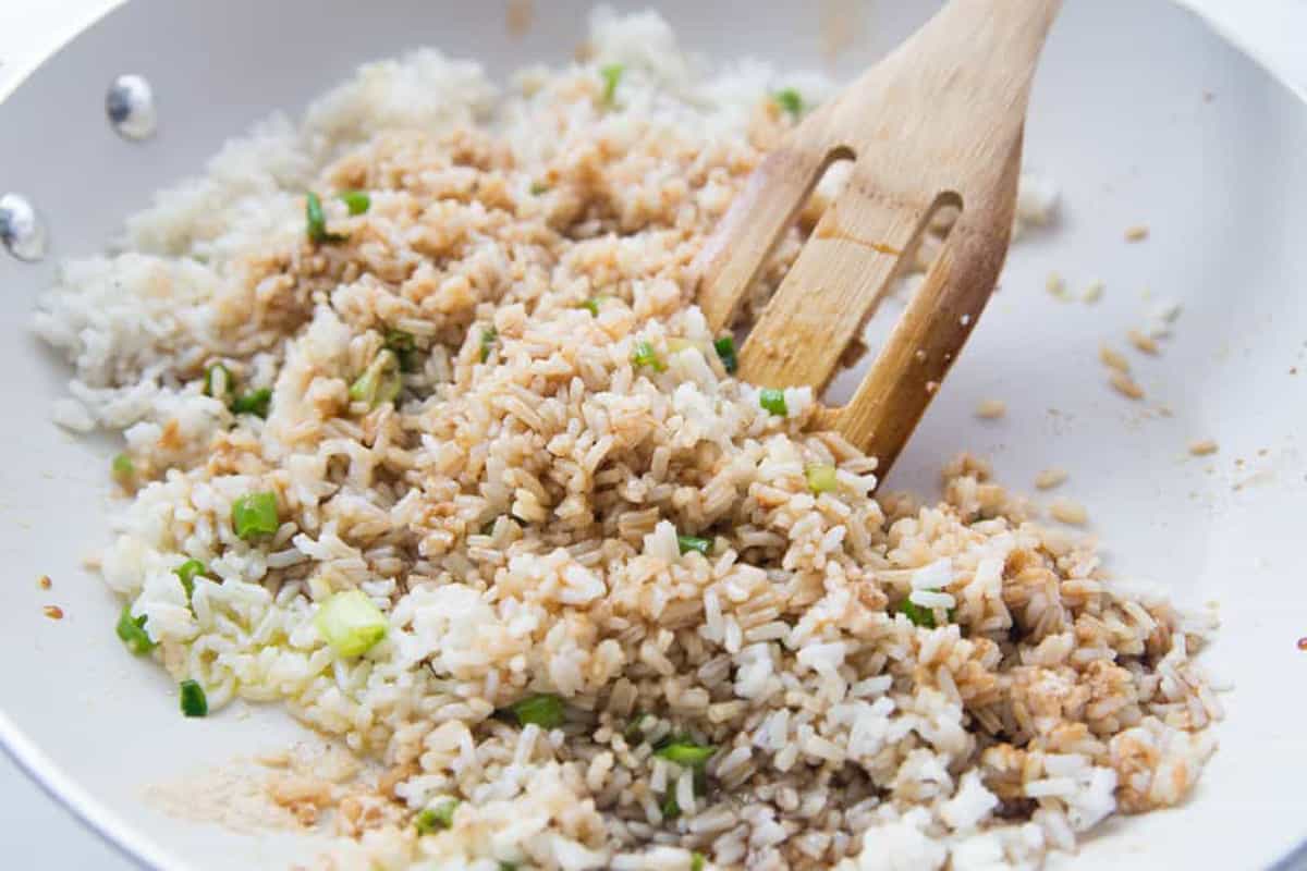 Rice, Oil and Green Onions in a frying pan. 