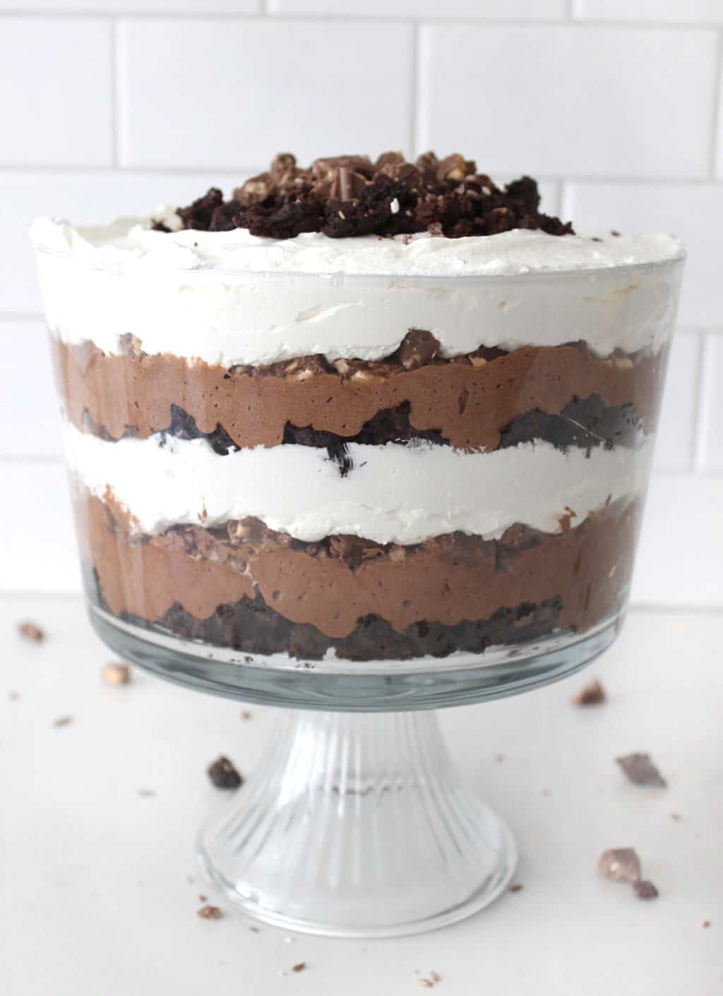 A side on view of a chocolate trifle with crumbs on a white counter. 