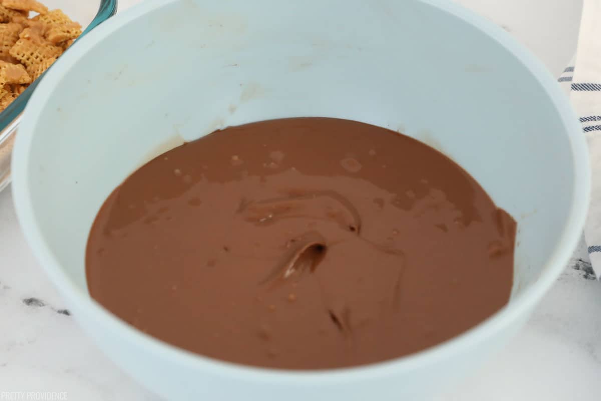Scotcheroos chocolate topping, chocolate chips melted in a light blue bowl.