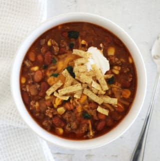 A bird's eye view of a white bowl of taco soup with all the toppings.