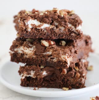 Three rocky road brownies stacked on a small white plate.