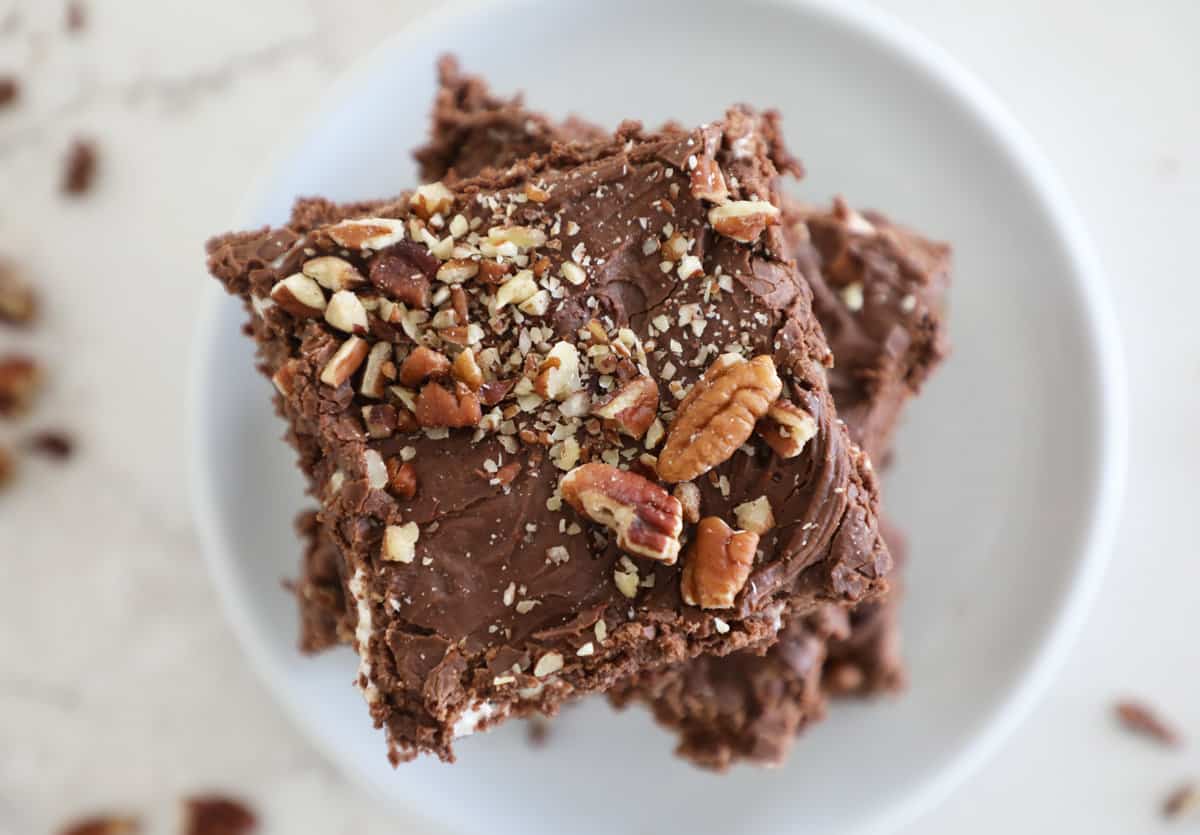 Chocolate brownies with chocolate frosting and chopped pecans on top.
