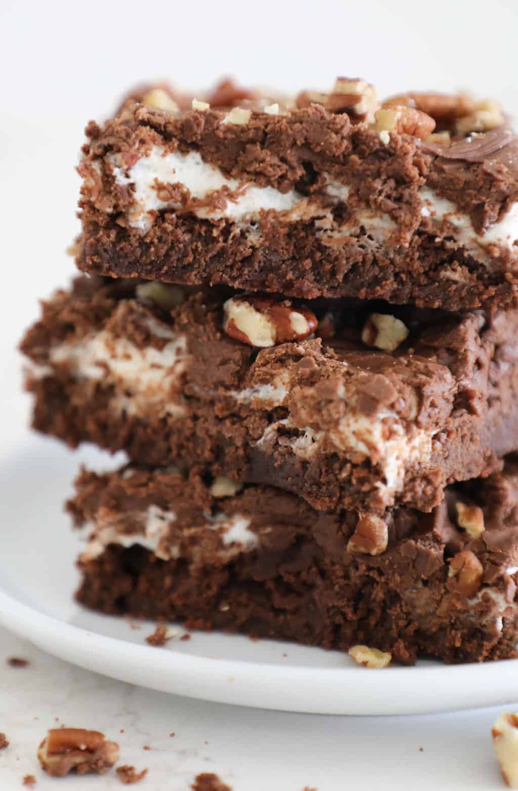 Side view of the different layers in a rocky road brownie, brownie, marshmallows, frosting and nuts.