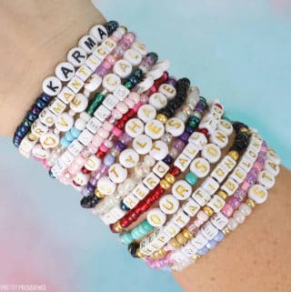 Taylor Swift bracelet ideas lots of bead bracelets with taylor swift song names on them on a wrist.