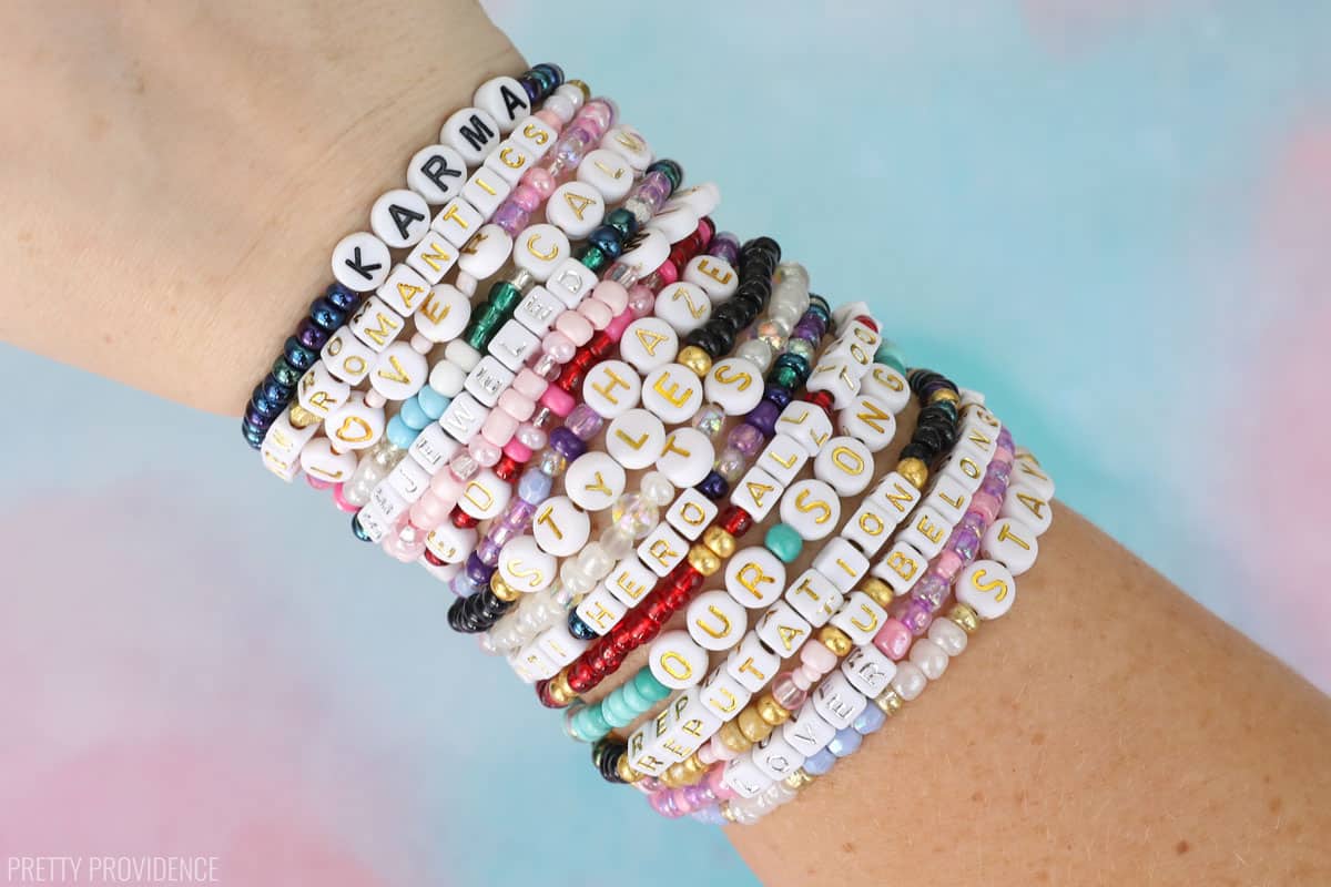 Taylor Swift bracelets for Eras tour, many friendship bracelets with colorful beads and letters on a wrist.