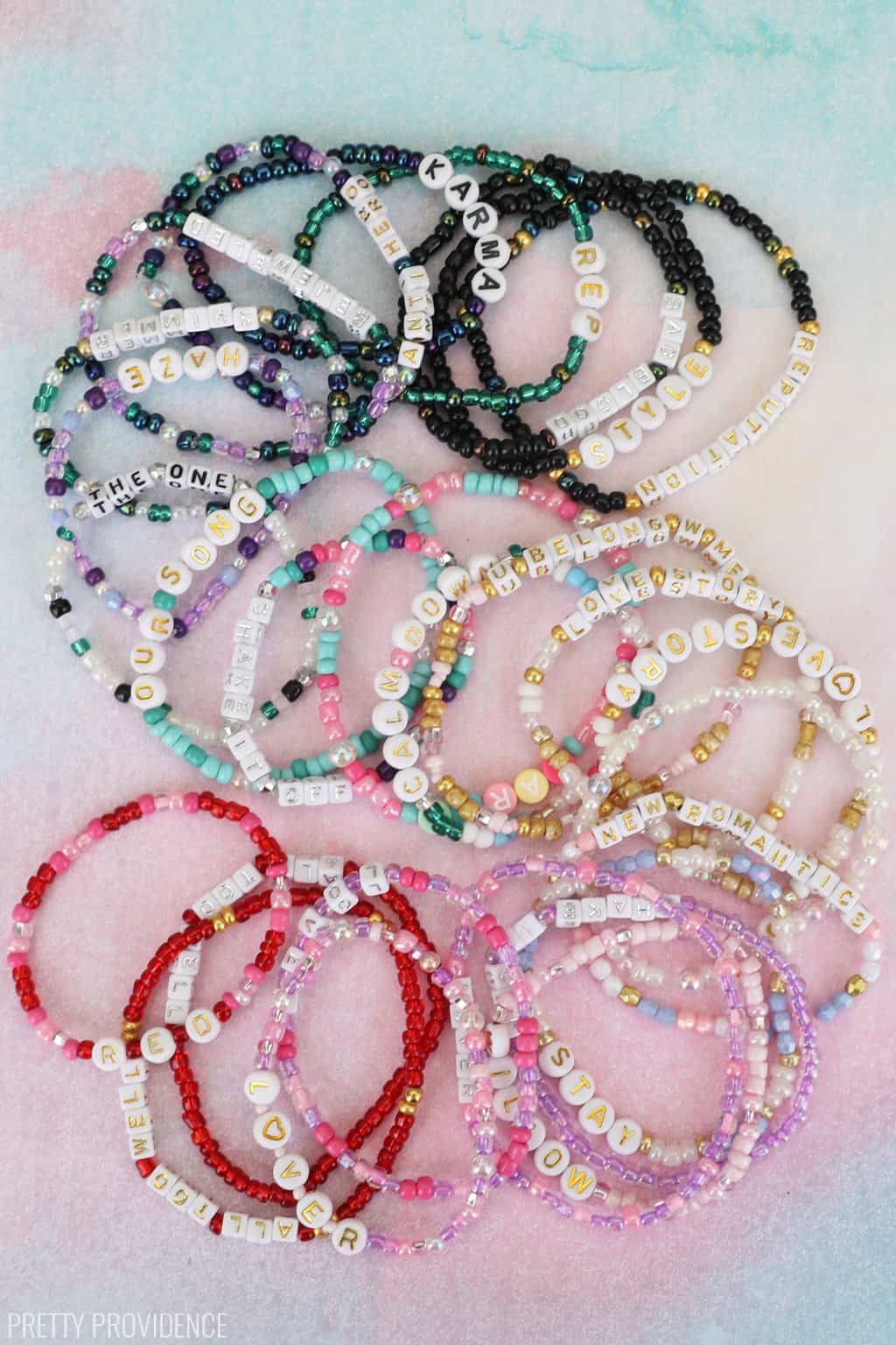 Taylor Swift bracelets ideas by album, friendship bracelets arranged by color on a pink and blue lover inspired backdrop. 
