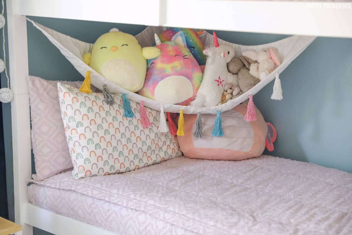 Girls bunk bed with light purple bedding and stuffed animal hammock.