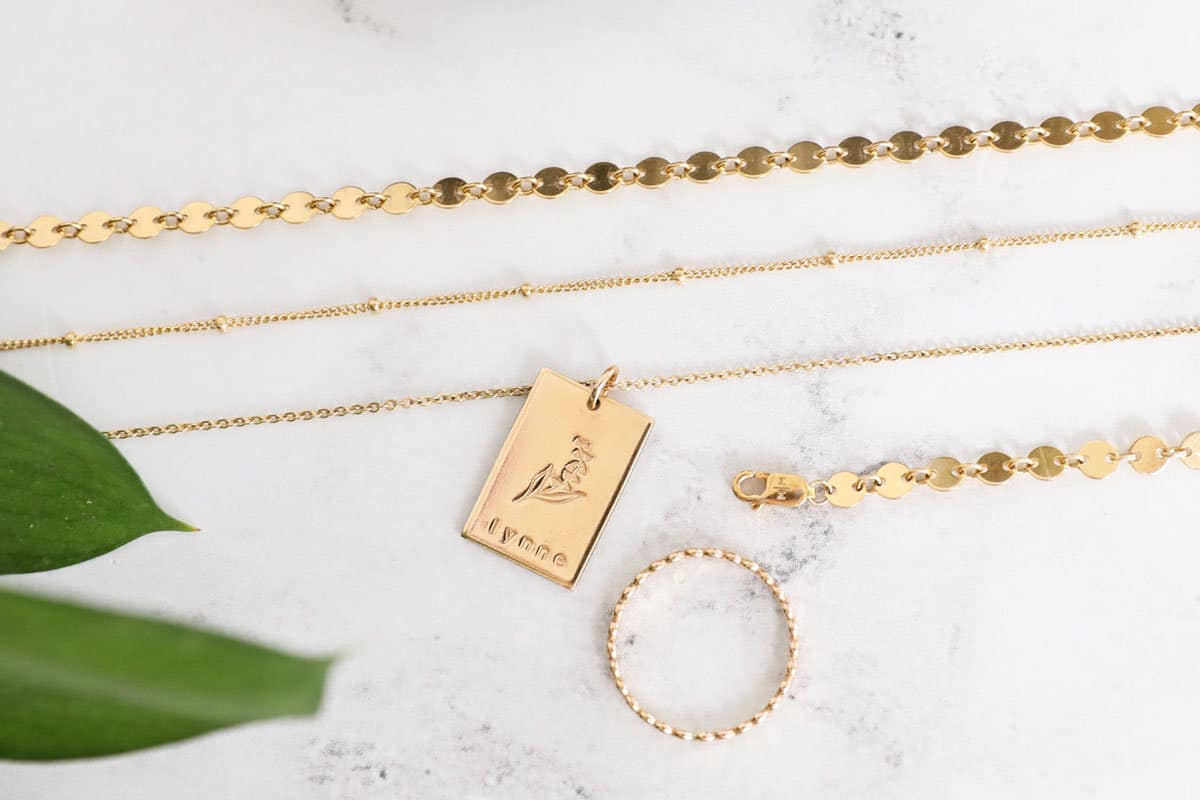 Three necklaces and a bracelet and ring on a pretty countertop. 