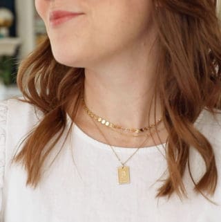A close up image of a woman in a white shirt wearing Made by Mary necklaces.