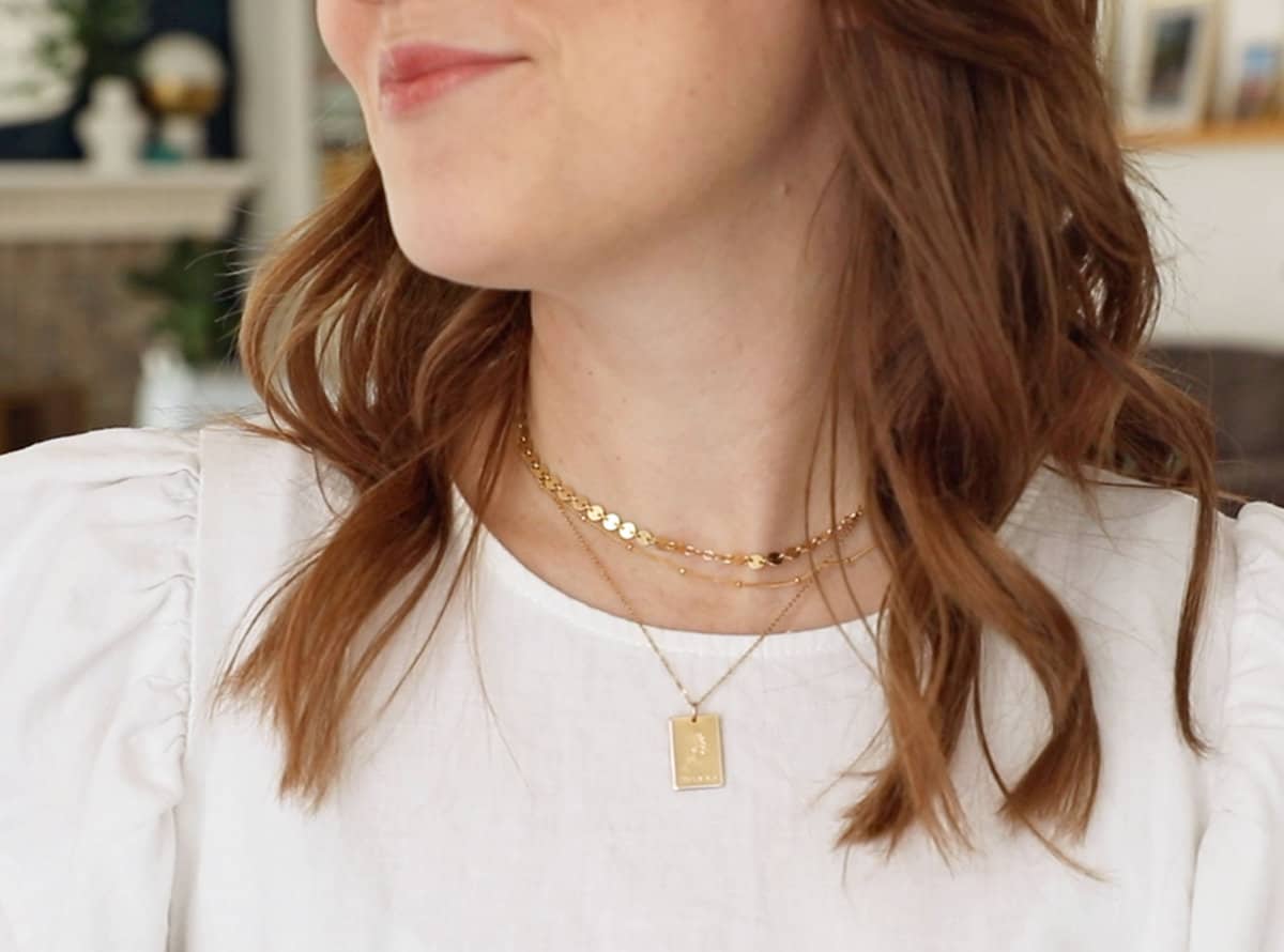 A close up image of a woman in a white shirt wearing Made by Mary necklaces.