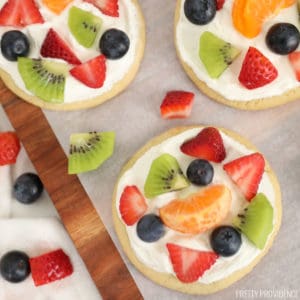 Sugar cookies topped with white frosting and sliced kiwi, blueberries, mandarin oranges and strawberries.